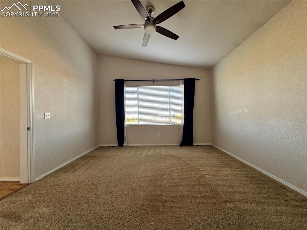 Image 18 of 36: Empty room featuring vaulted ceiling, ceiling fan, and light colored carpet