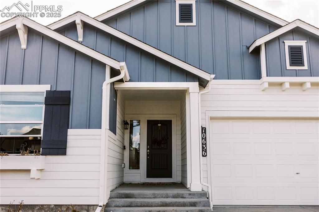Image 2 of 36: Entrance to property featuring board and batten siding and a garage