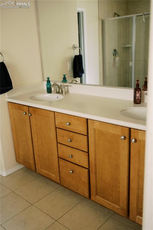 Image 22 of 36: Full bath with double vanity, tile patterned floors, and a shower stall