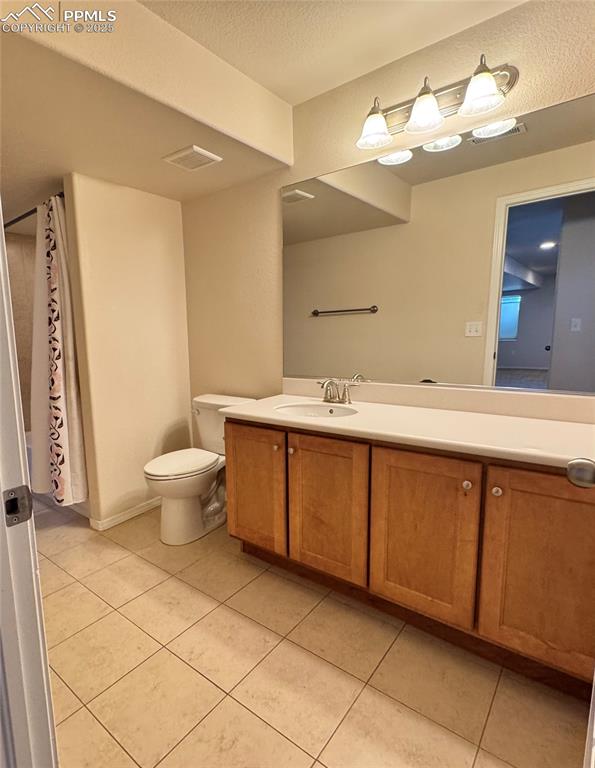 Image 31 of 36: Full bathroom with tile patterned flooring, vanity, a textured ceiling, and