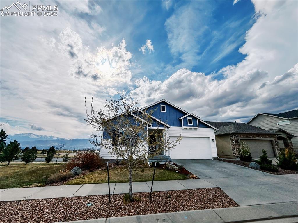 Image 4 of 36: View of front of house with board and batten siding, concrete driveway, and