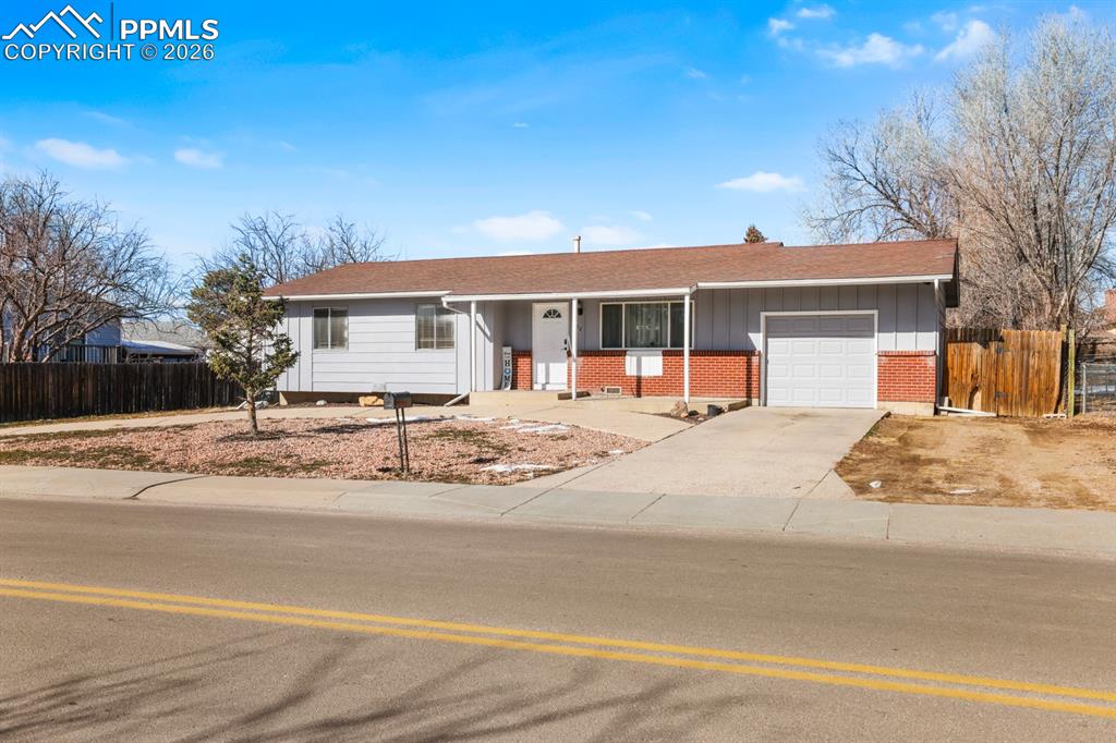 Image 12 of 37: Ranch-style house with covered porch, concrete driveway, brick siding, and 
