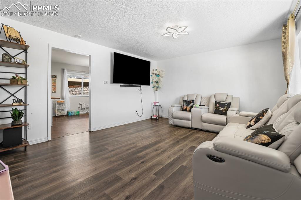 Image 14 of 37: Living room with dark wood finished floors and a textured ceiling