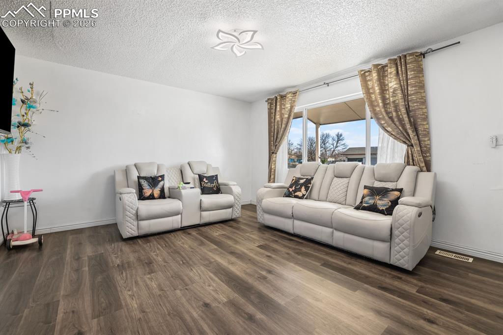 Image 16 of 37: Living room featuring dark wood-type flooring and a textured ceiling