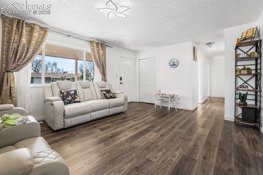 Image 17 of 37: Living room with wood finished floors and a textured ceiling