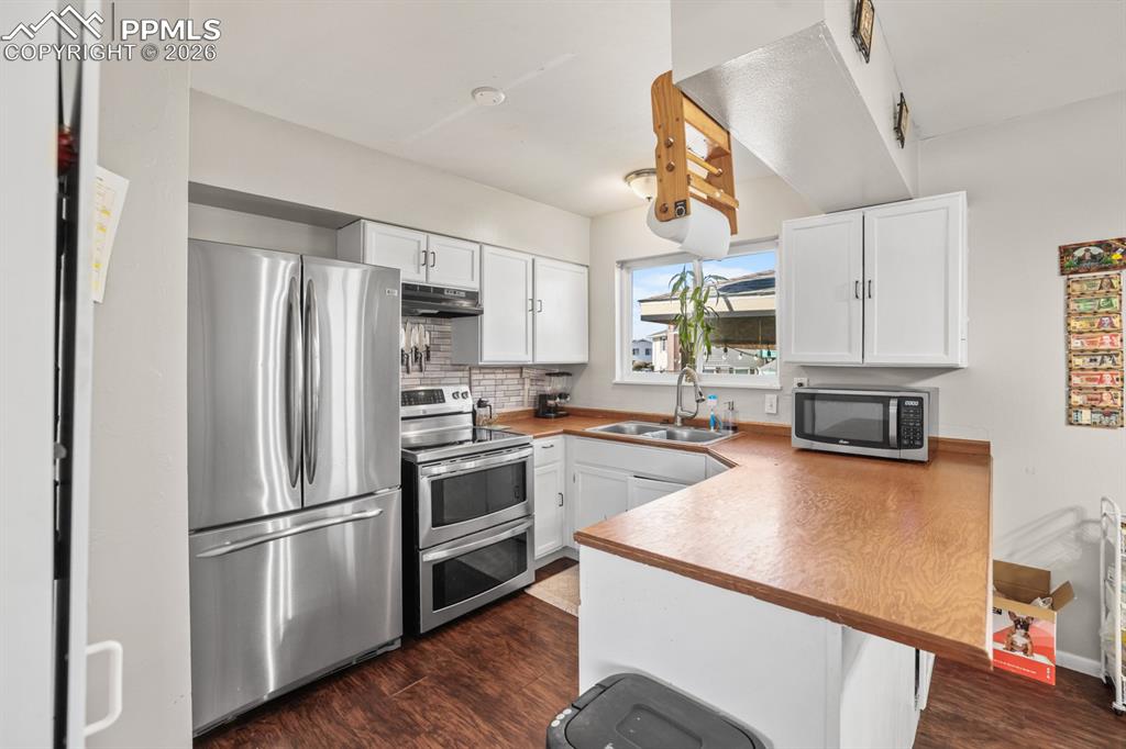 Image 18 of 37: Kitchen featuring white cabinets, stainless steel appliances, a peninsula, 