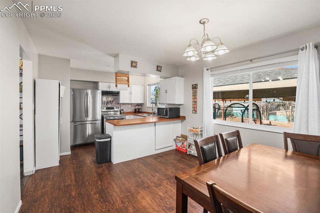 Image 20 of 37: Dining area featuring suspended lighting and dark wood-style flooring