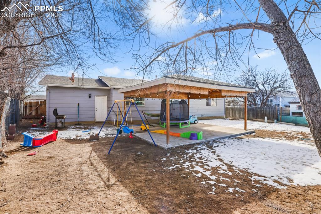 Image 34 of 37: Rear view of property featuring a playground, a fenced backyard, a patio ar