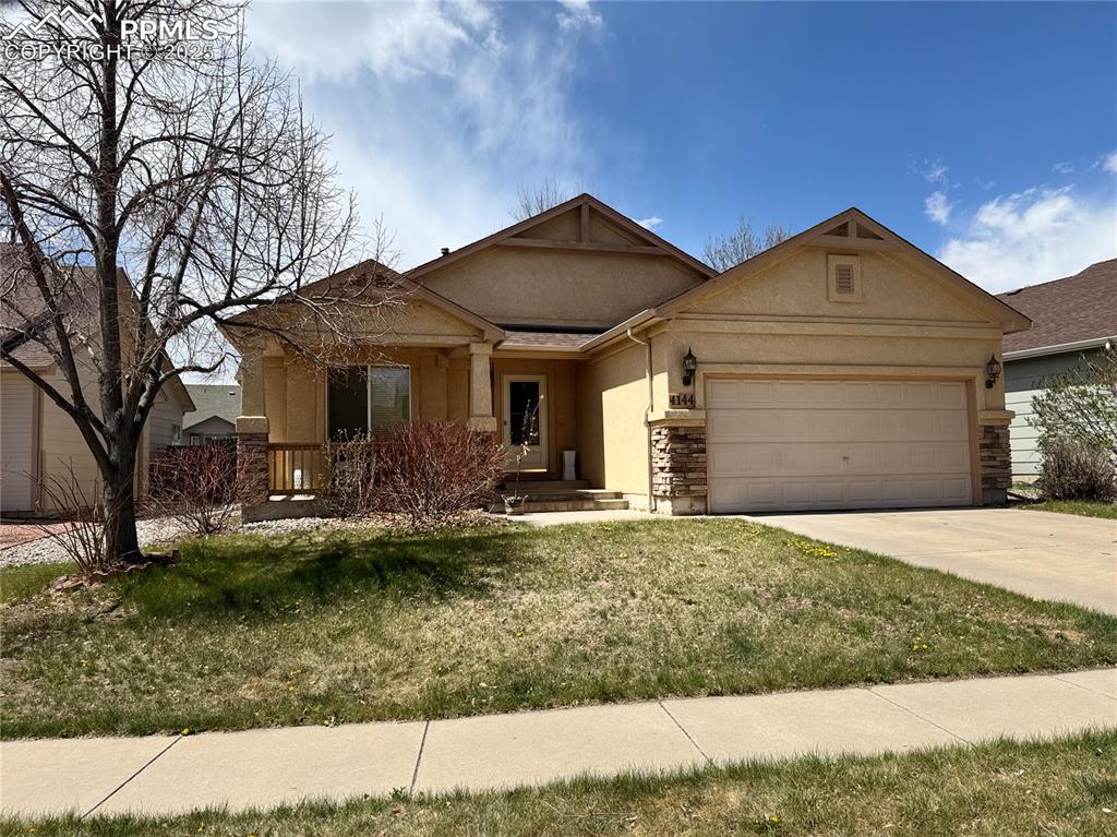 Caption: Single story home featuring stucco siding, driveway, stone siding, a front yard, and a garage