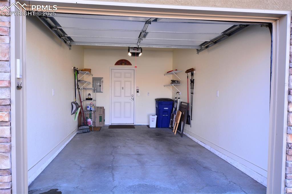 Image 22 of 37: Garage with electric panel and a garage door opener