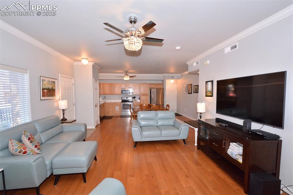 Image 8 of 37: Living room featuring light wood-type flooring, ceiling fan, and ornamental