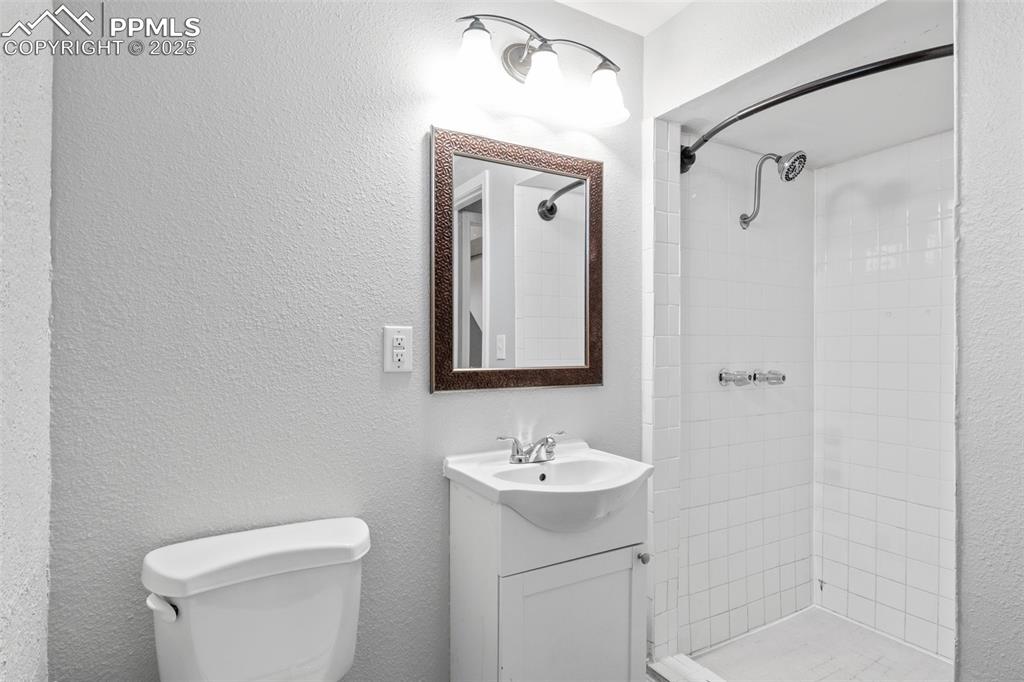 Image 15 of 25: Bathroom featuring a textured wall, vanity, and a shower stall