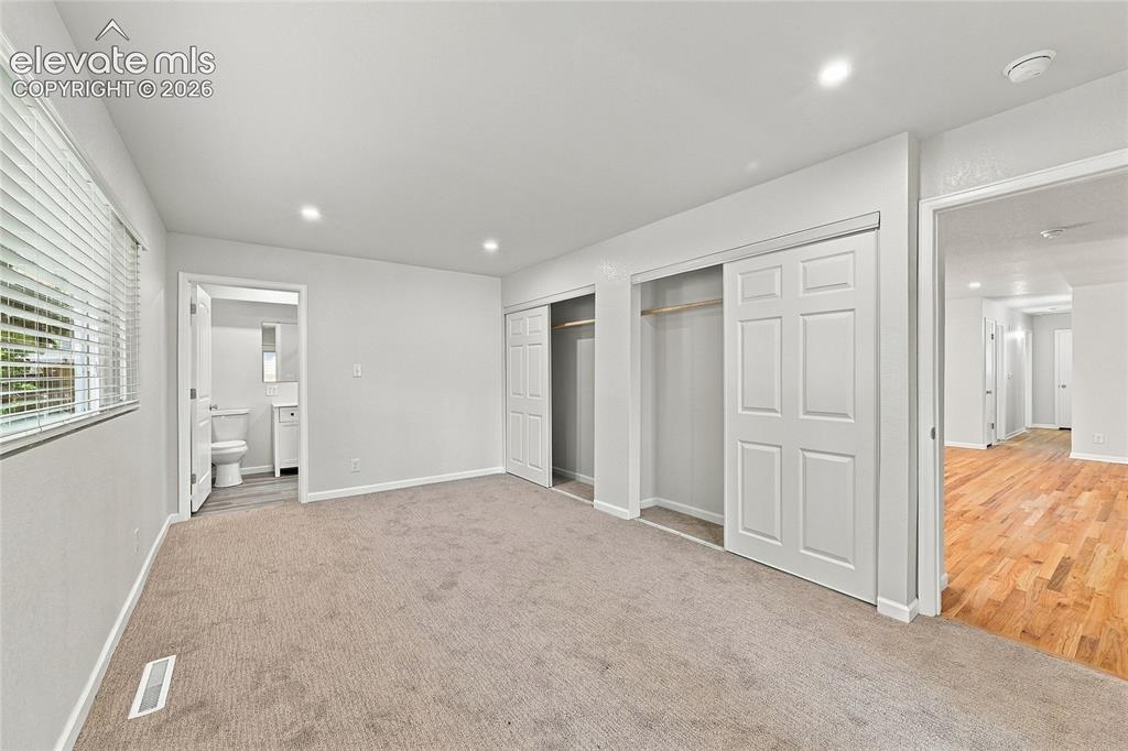 Image 15 of 49: Carpeted room with recessed lighting, two sliding closet doors, and access