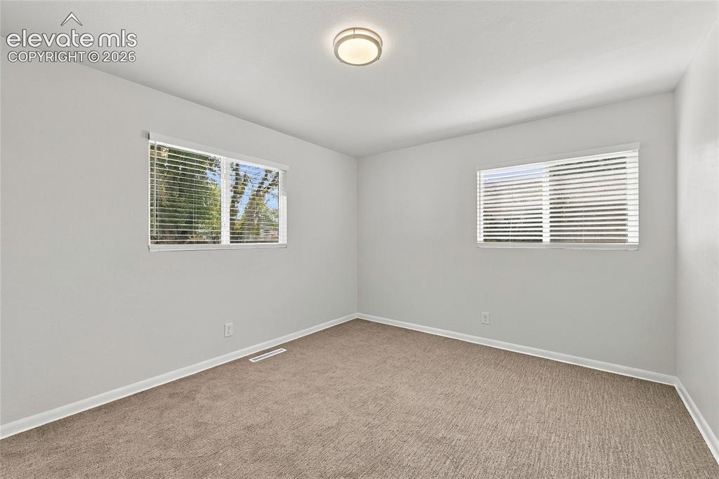 Image 21 of 49: Neutral wall color, two windows with blinds, flush mount ceiling light, and