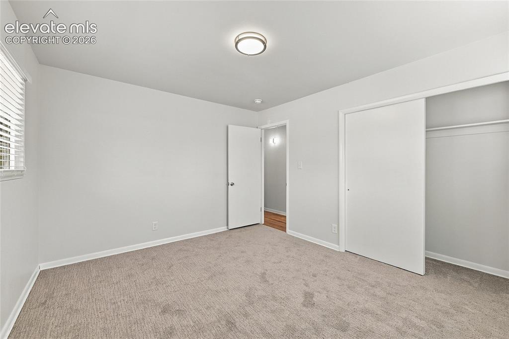 Image 26 of 49: Neutral tone wall paint, flush mount ceiling light fixture, window with hor