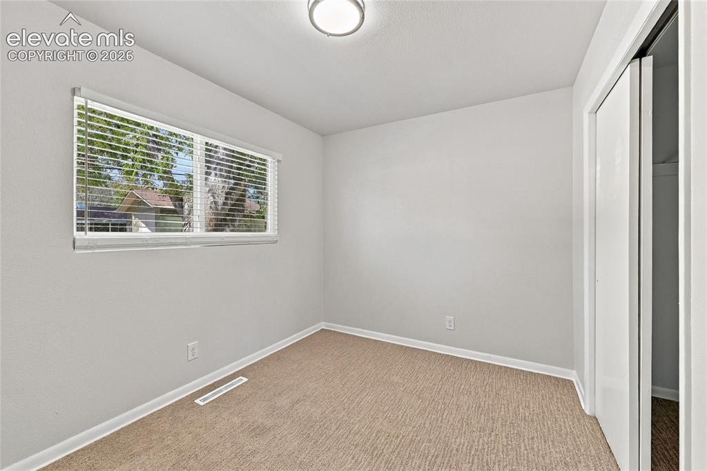 Image 27 of 49: Neutral wall color, window with blinds, flush mount ceiling light, and carp