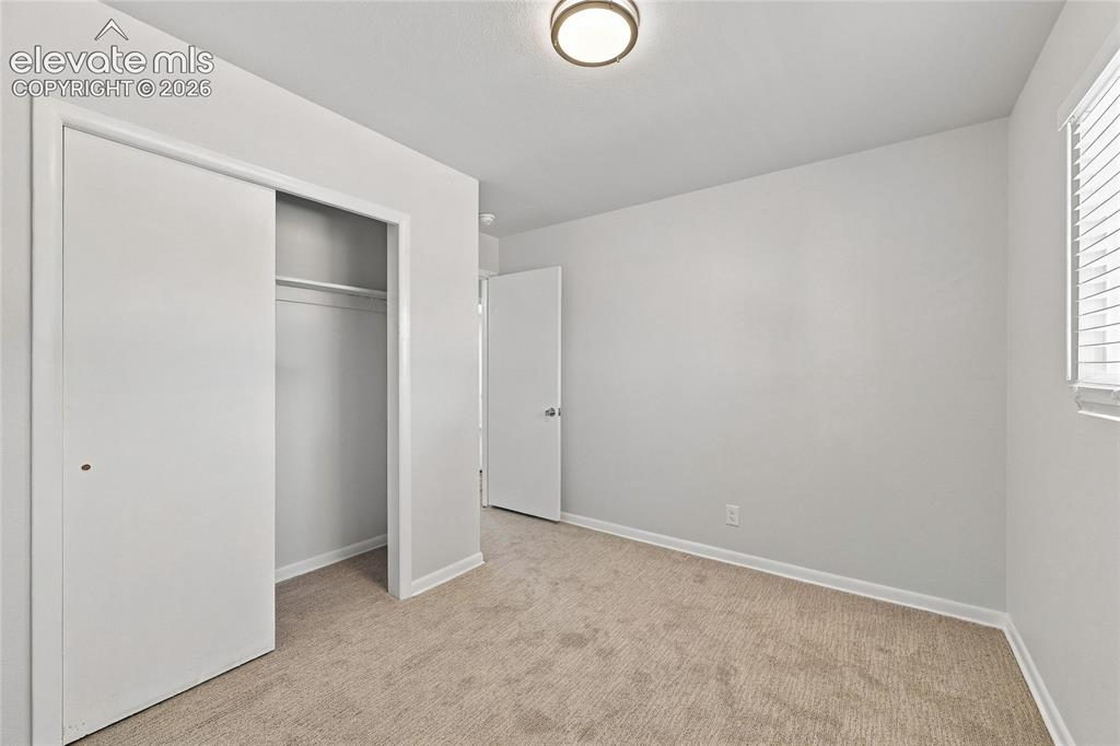 Image 28 of 49: Carpeted flooring, white walls, flush mount ceiling light, sliding closet d