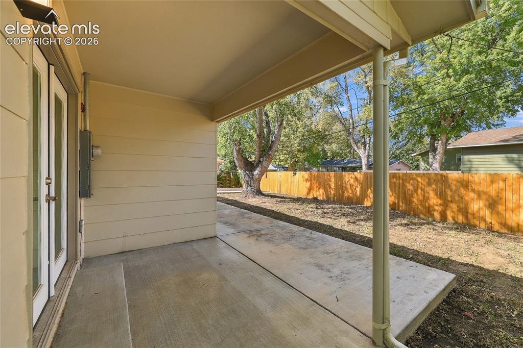 Image 29 of 49: Covered concrete patio with direct outdoor access through double French doo