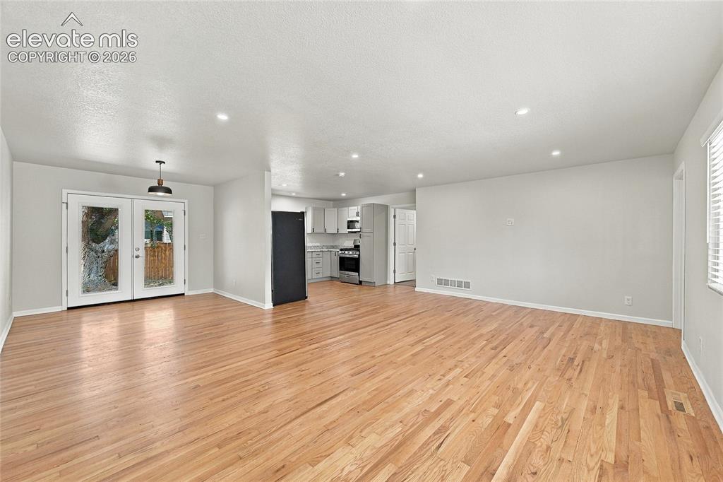 Image 5 of 49: Open-concept living area with wood-finish flooring, recessed lighting, and 
