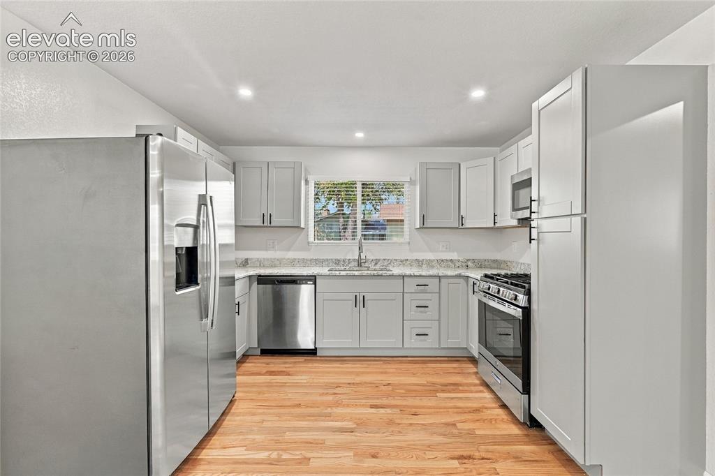 Image 8 of 49: White shaker-style cabinetry, stainless steel appliances, light-toned wood-