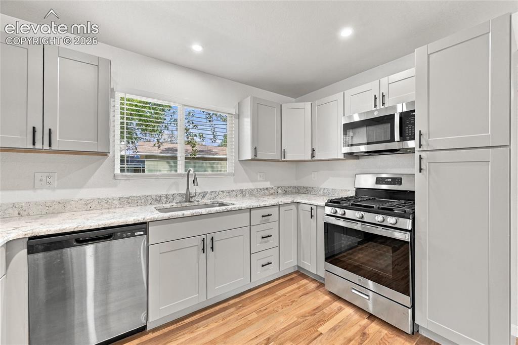 Image 9 of 49: Contemporary kitchen featuring light gray shaker cabinetry, stainless steel