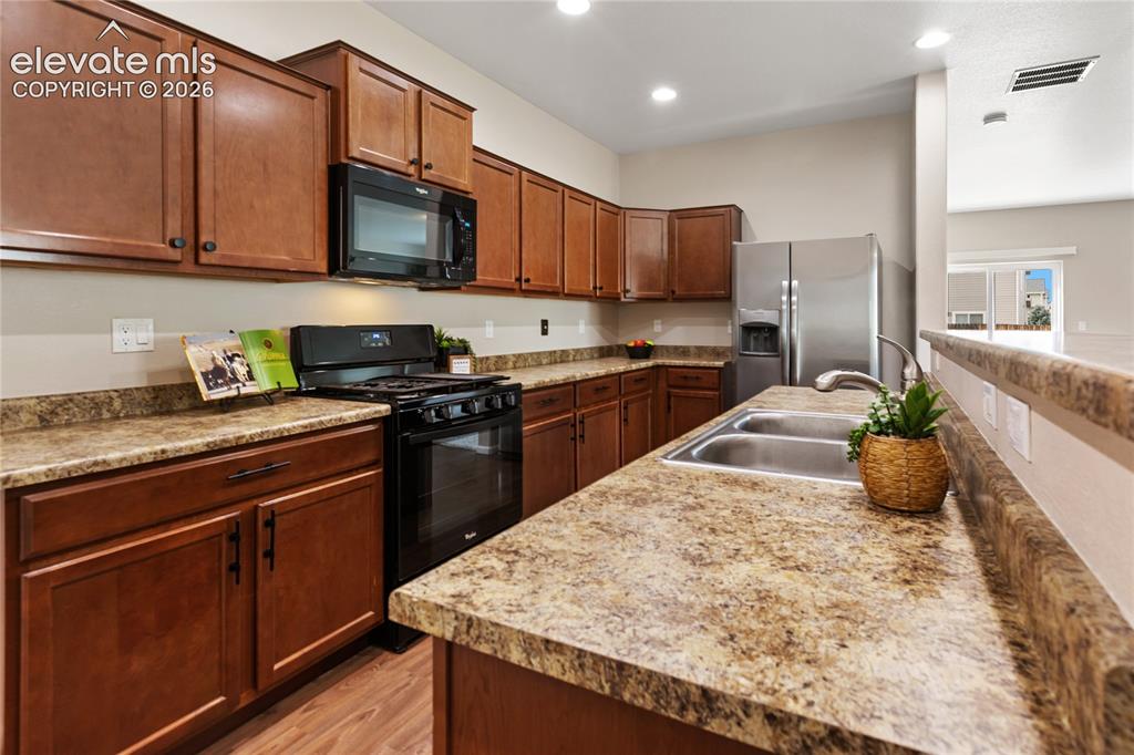 Image 18 of 46: Kitchen features gas range/oven, stainless steel refrigerator and a kitchen