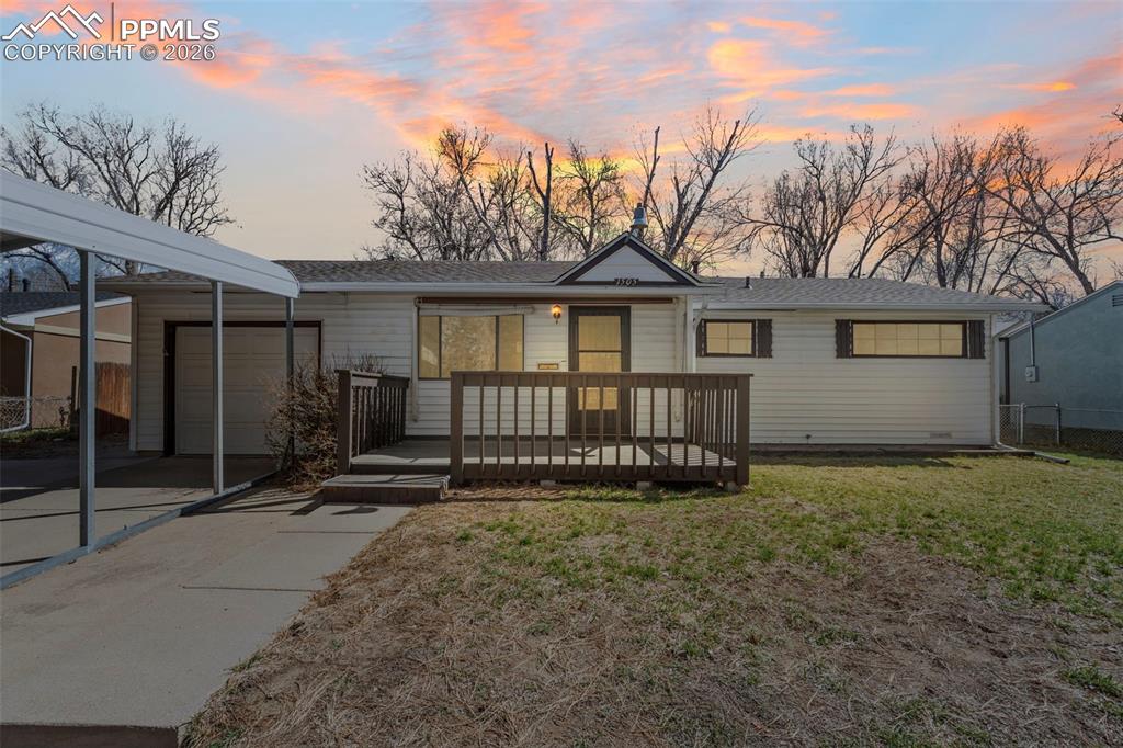 Image 1 of 18: View of front of home with a wooden deck, a front yard, an attached garage,