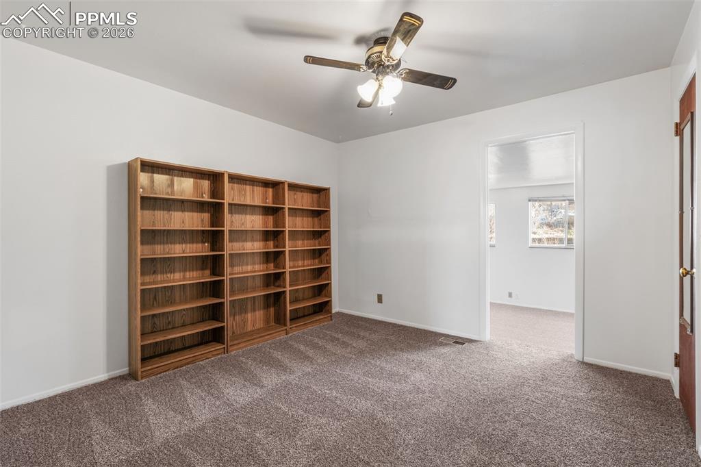 Image 12 of 18: Non-conforming bedroom/office with bookshelves, ceiling fan & new carpet