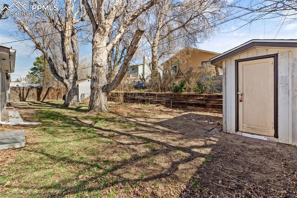 Image 15 of 18: Fenced backyard with a storage shed