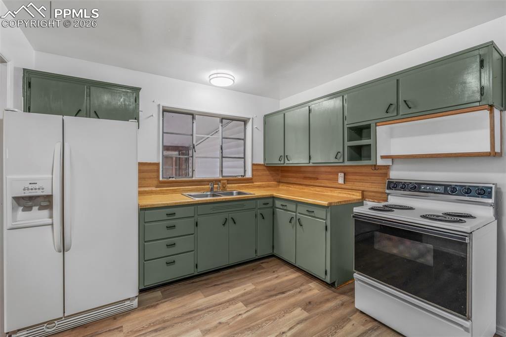 Image 5 of 18: Kitchen featuring green cabinets, white appliances, light countertops, ligh