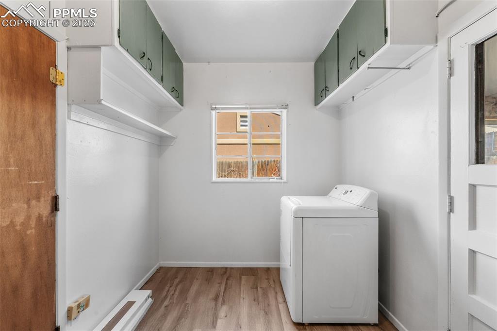 Image 7 of 18: Laundry area with washer / dryer, light wood-style flooring, and cabinet sp
