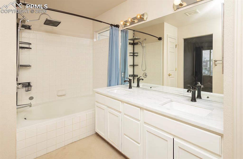 Image 14 of 35: Bathroom featuring a dual vanity with white cabinetry and a light-toned cou
