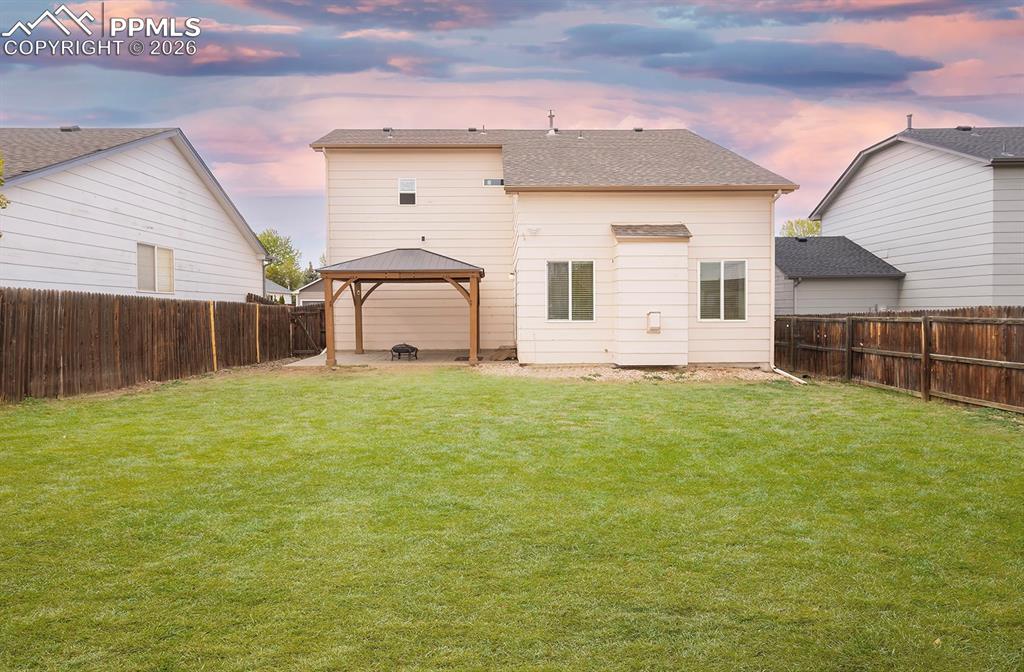 Image 20 of 35: Expansive backyard featuring a manicured lawn, a detached gazebo with a dar