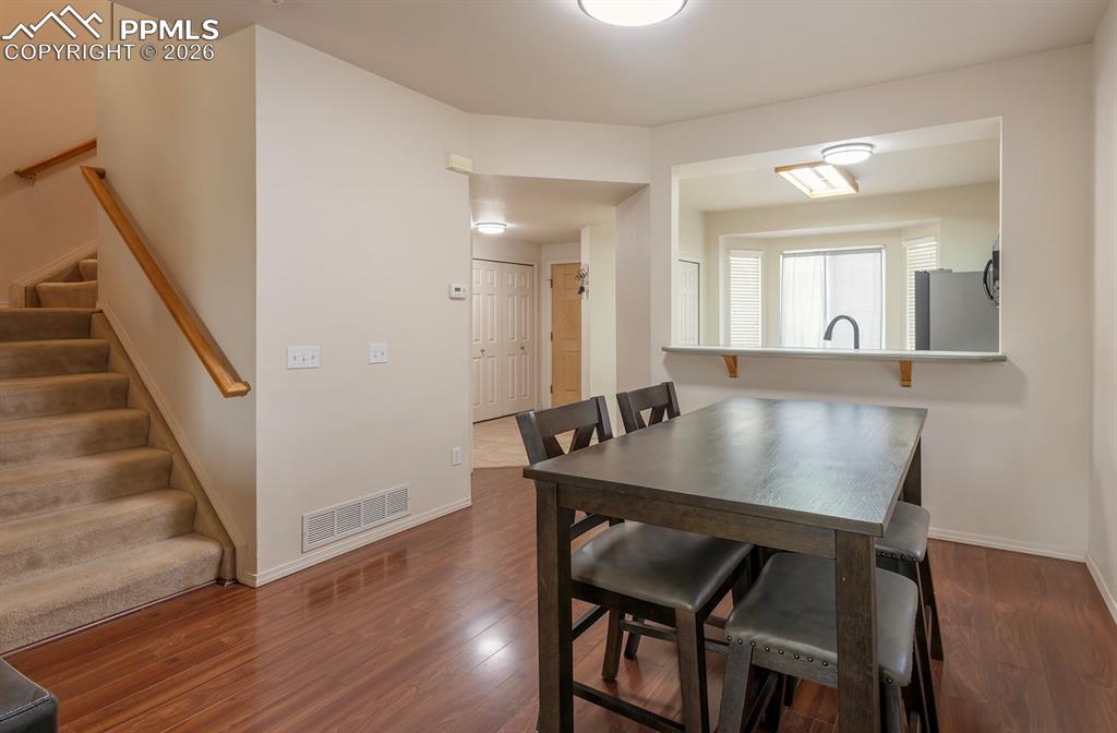 Image 26 of 35: Open-concept living area featuring wood-finish flooring, a carpeted stairca