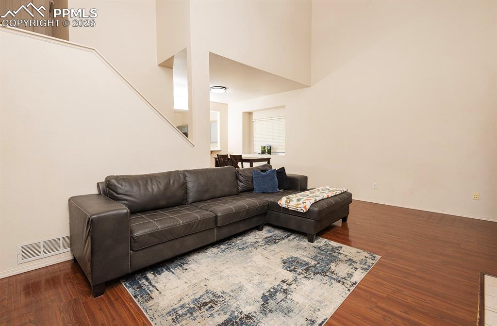 Image 28 of 35: Spacious living area featuring wood-finish flooring, high ceilings, and a n