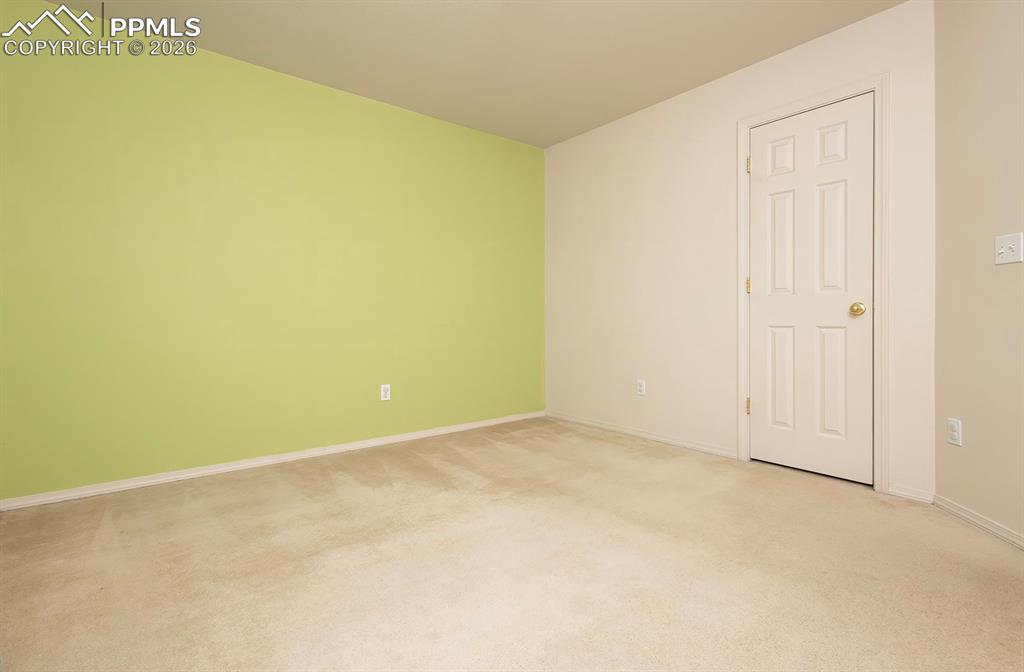 Image 30 of 35: Room featuring neutral carpet flooring, a light green accent wall, and a si