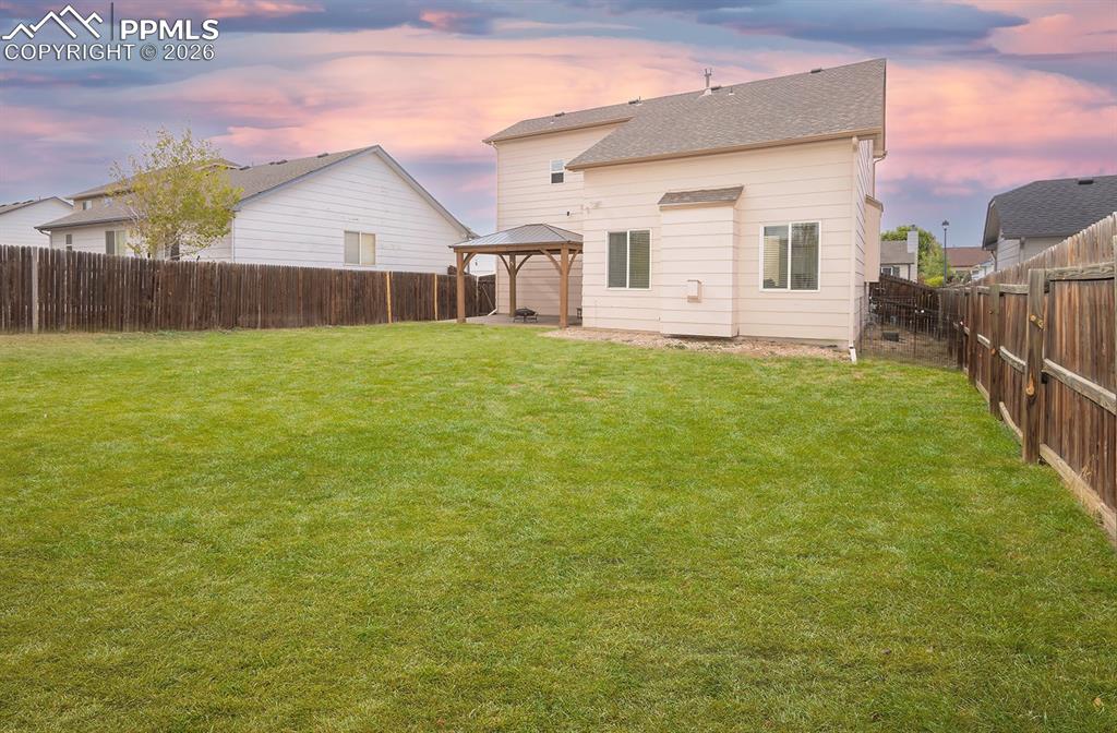 Image 5 of 35: Expansive rear yard featuring a large grass lawn, perimeter wood fencing, a
