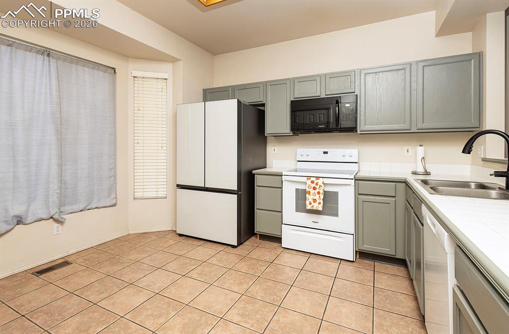 Image 8 of 35: Kitchen featuring gray cabinetry, light-colored countertops, and tile floor