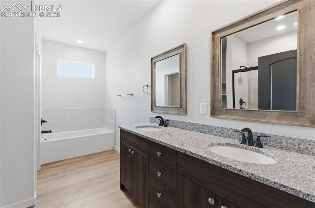 Image 16 of 24: Full bath with double vanity, light wood-type flooring, a shower stall, a b