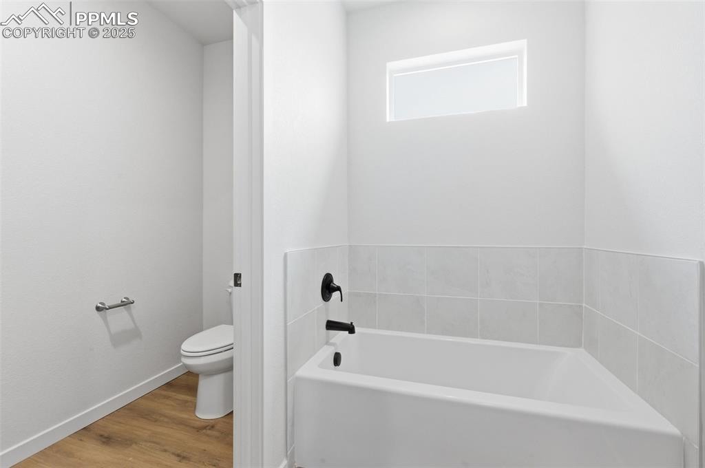 Image 18 of 24: Bathroom featuring a bath and wood finished floors