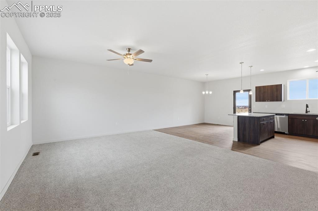 Image 2 of 24: Kitchen with dark brown cabinetry, a kitchen island, open floor plan, light