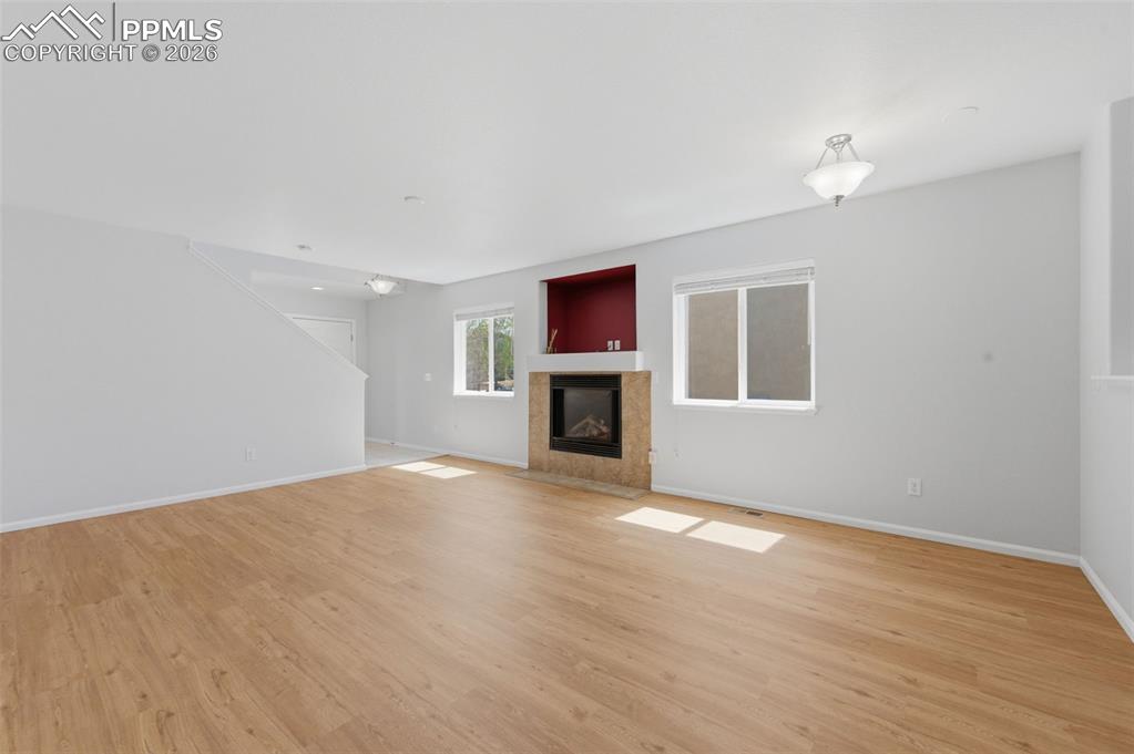 Image 10 of 34: Spacious living area featuring light wood-look LVP flooring, a contemporary
