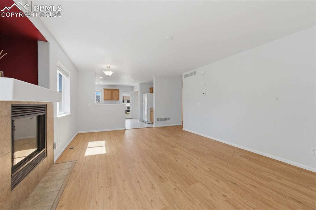 Image 13 of 34: Living area featuring wood-look LVP flooring, a tiled fireplace with a mant