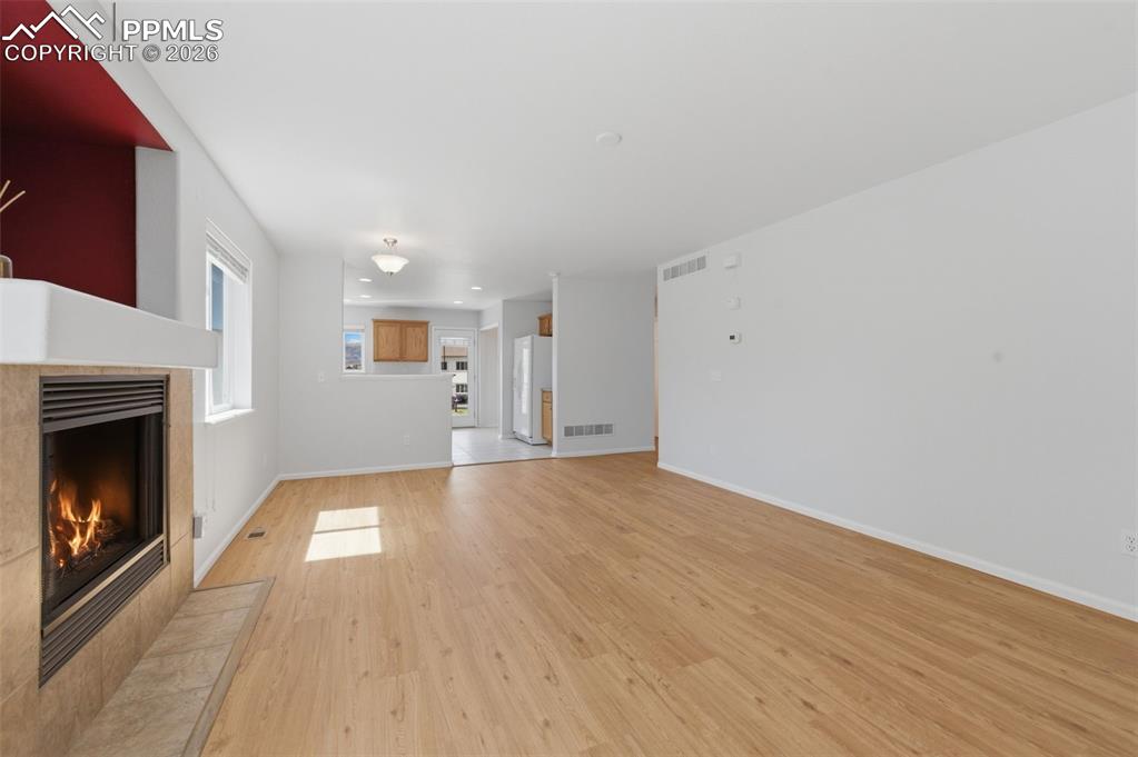 Image 14 of 34: Living area featuring light wood-look flooring and a fireplace with a Tiled