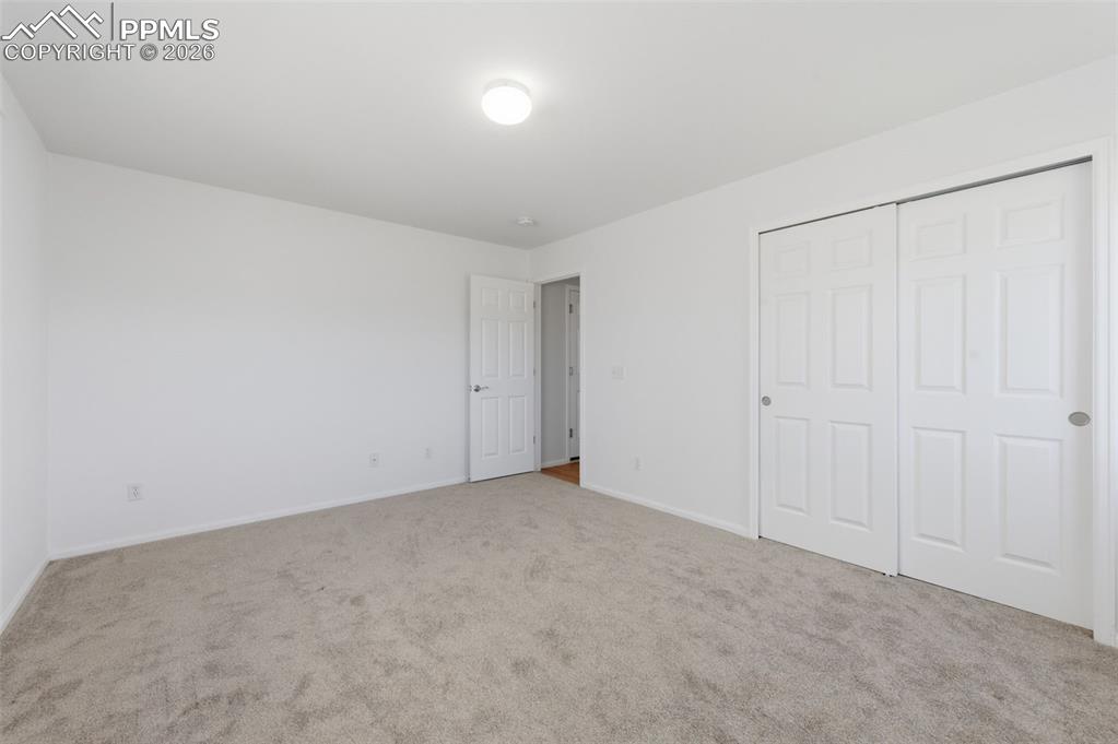 Image 18 of 34: Carpeted main level bedroom featuring white walls and a white ceiling with 
