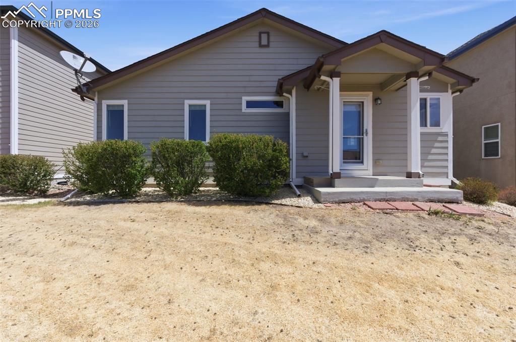 Image 27 of 34: Grey siding exterior featuring a covered entry porch, white frame windows, 