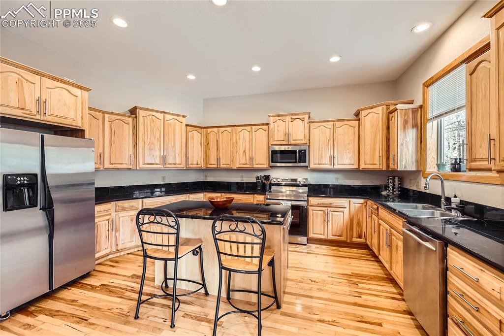 Image 12 of 50: Kitchen with light brown cabinets, a sink, a kitchen breakfast bar, a kitch