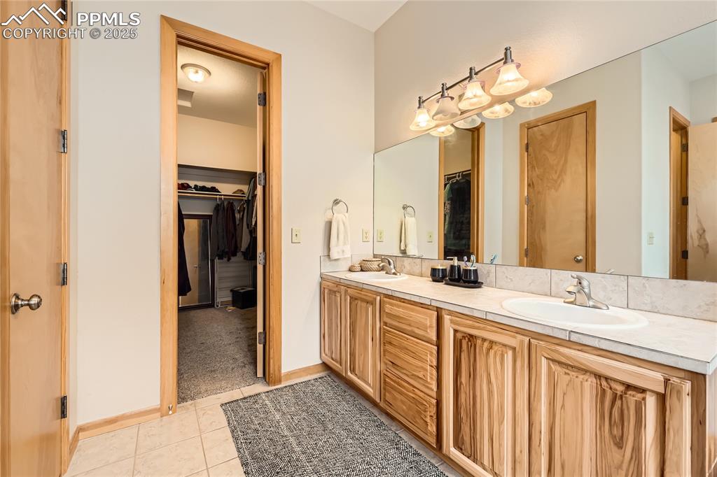 Image 19 of 50: Bathroom featuring tile patterned floors, a spacious closet, double vanity,