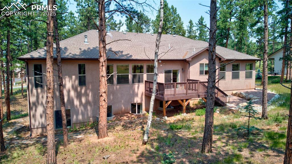 Image 41 of 50: Back of house featuring stairway, stucco siding, a shingled roof, and a dec