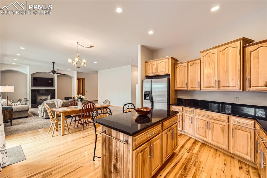 Image 9 of 50: Kitchen with light wood-style flooring, a tiled fireplace, recessed lightin